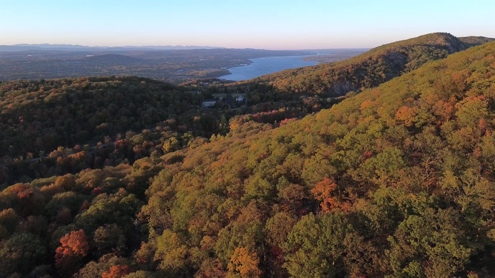 Aerial view of wooded Finger Lakes hillsides in autumn above the lake